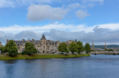 Stately building by river against cloudy sky. 