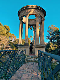 Rear view of woman standing on railing against sky