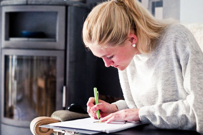 Young woman writing on paper at home
