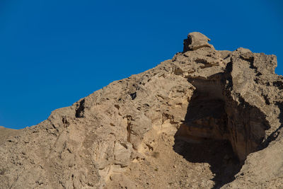Low angle view of rock formation against clear blue sky