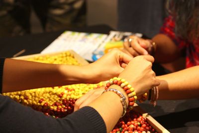 Cropped image of friend tying bracelet to woman