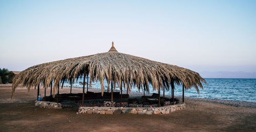 Stilt house on beach against clear sky