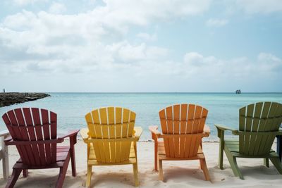 Chairs and tables on beach against sky