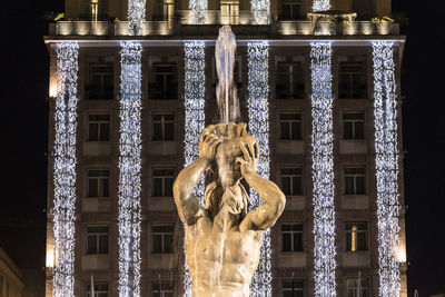 Low angle view of statue against illuminated building