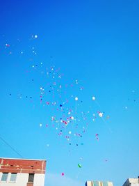 Low angle view of balloons flying against blue sky