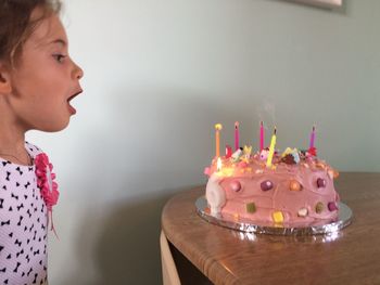 Close-up of girl blowing candles on cake at home