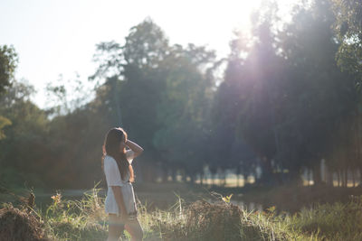 Rear view of woman standing by trees against sky