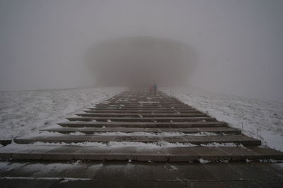 People on staircase covered with snow against sky