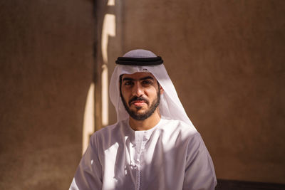 Portrait of young man standing against wall