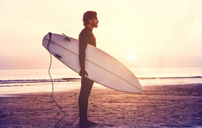 Man with surfboard standing at beach