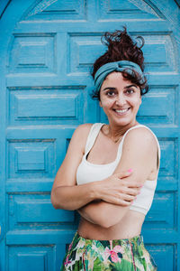 Portrait of smiling young woman standing against wall