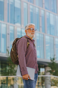 An adult man with a laptop outside the office. grey-haired european senior businessman