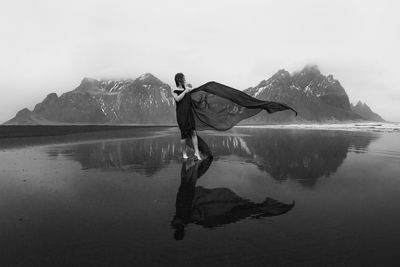 Lady with red waving fabric on northern beach monochrome scenic photography