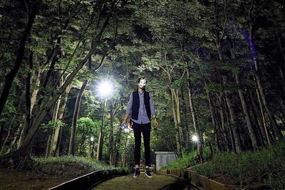 Young man standing by tree in forest