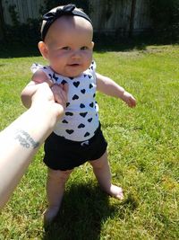 Portrait of cute baby girl standing on field