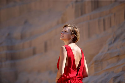 Woman looking away while standing against wall