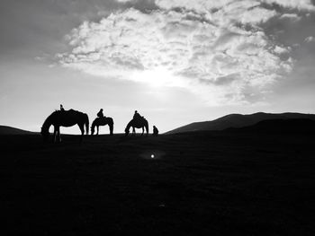 Silhouette of men on horse on mountain