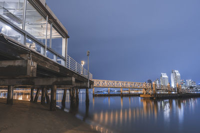 Bridge over river against sky in city at night