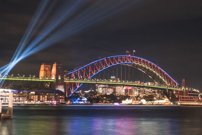 Illuminated bridge over river at night