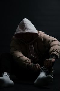 Rear view of a man sitting against black background