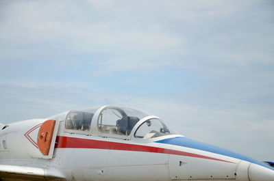 Airplane flying over airport runway against sky