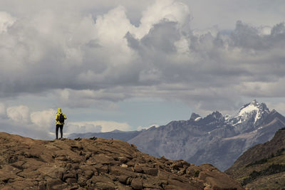 Rear view of man standing on mountain against sky