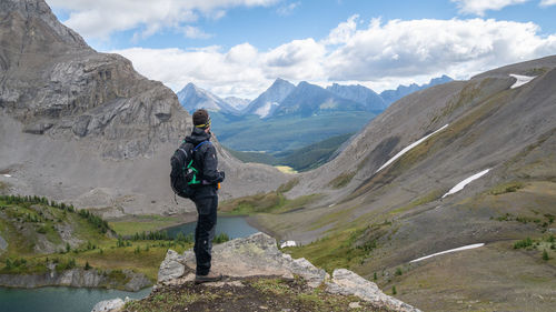 Male hiker overlooking alpine valley from top of the mountain, canadian rockies, canada