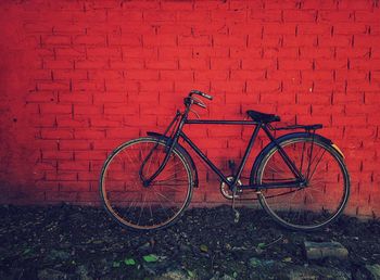 Bicycle parked against brick wall