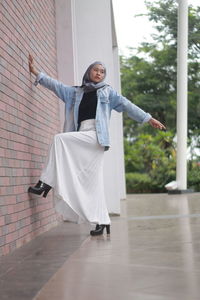 Full length of young woman standing against wall