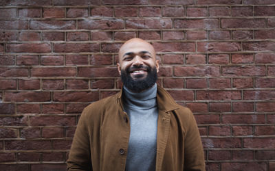 Portrait of young man against brick wall