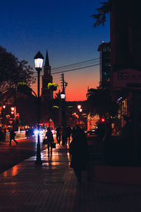 Silhouette people on illuminated street at night