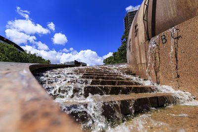 Water flowing through built structure against sky
