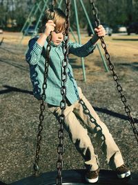 Full length of boy playing on swing in playground