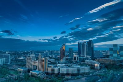 Aerial view of buildings in city against blue sky