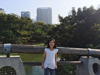 Portrait of smiling girl standing against trees