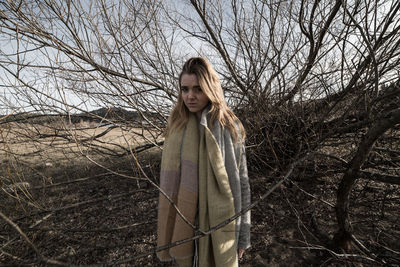 Portrait of woman standing amidst bare tree