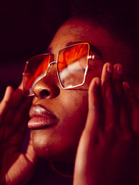 Young curly serious haired black female in stylish sunglasses and hoop earrings with eyes closed