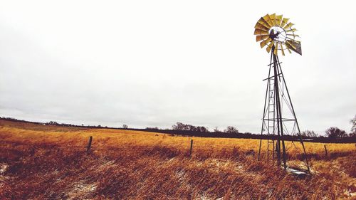 Low angle view of windmill on field against sky