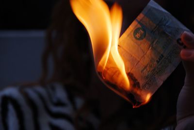 Cropped image of woman burning paper currency