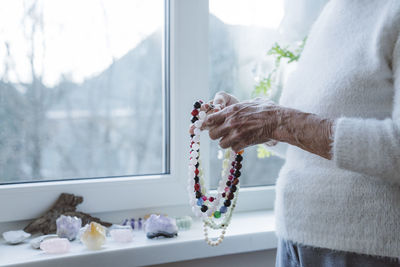 Hands of senior woman holding gemstone beads necklace