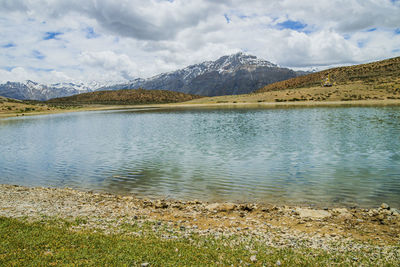 Scenic view of lake by mountains against sky