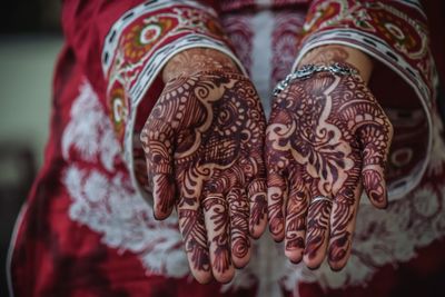 Midsection of bride showing henna tattoo on hands