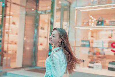 Young woman with eyes closed standing in store window
