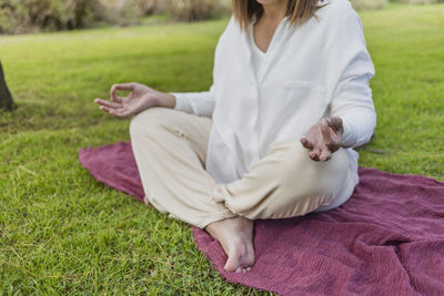 Low section of peaceful woman
 sitting on grass