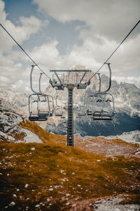 Overhead cable cars against cloudy sky during winter
