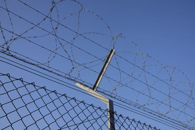 Low angle view of barbed wire against clear sky