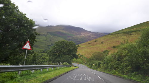 Road by mountains against sky