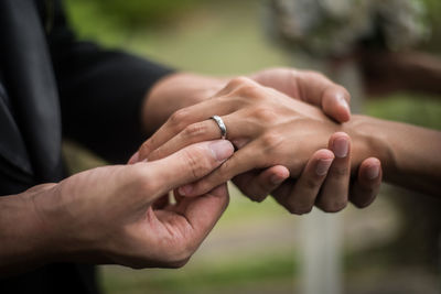 Bride and groom exchanging rings while holding hands