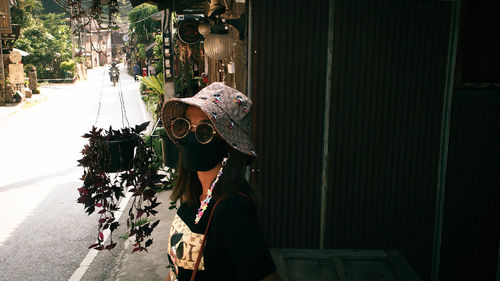 Side view of young woman standing by window