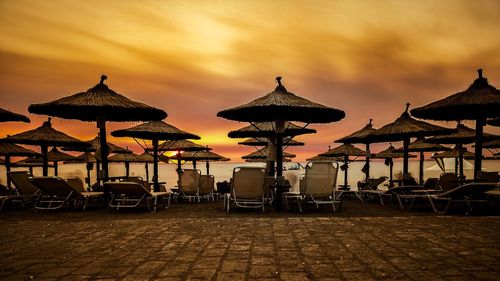 Parasols on beach against sky during sunset